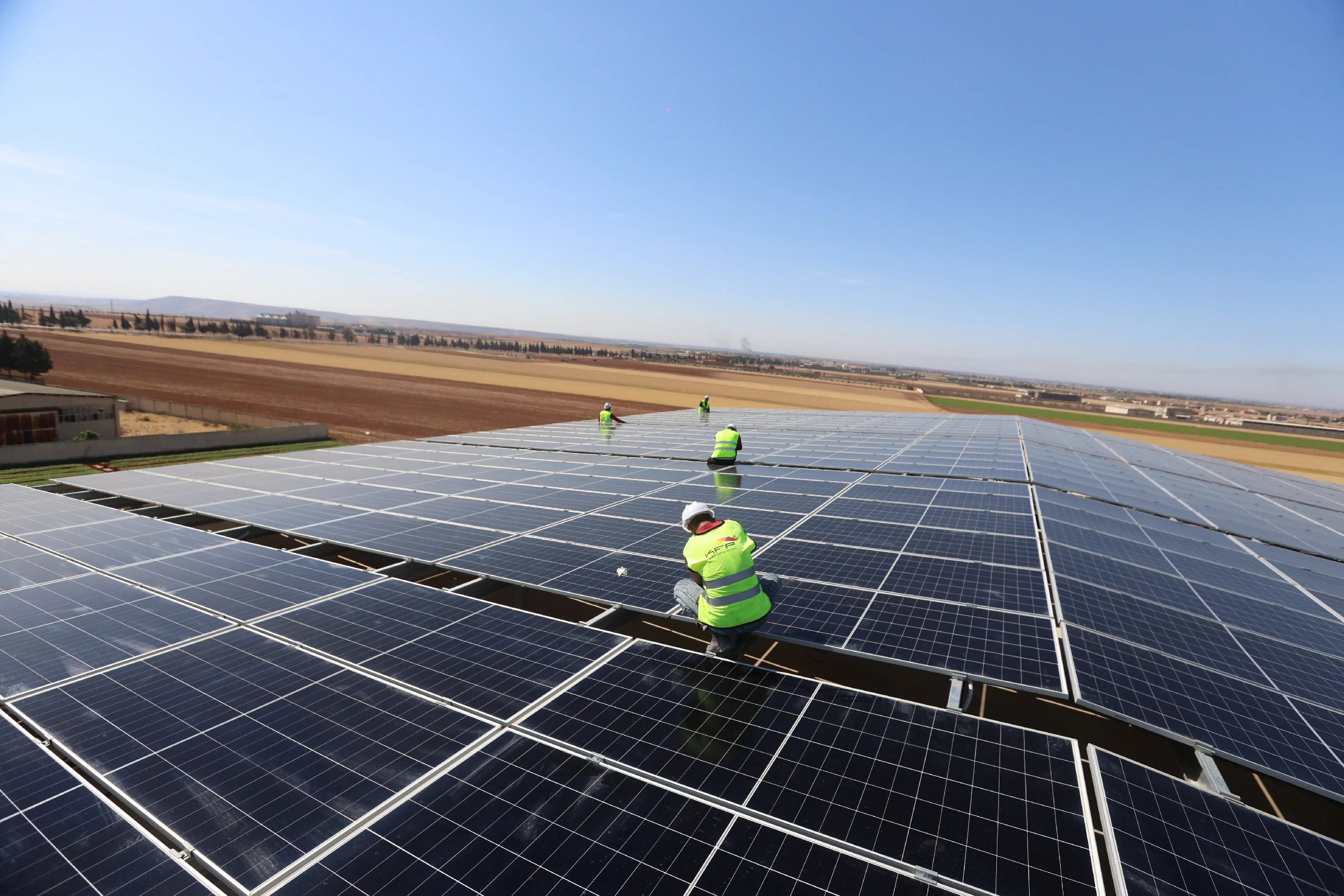 Solar PV technicians working on a large rooftop photovoltaic array